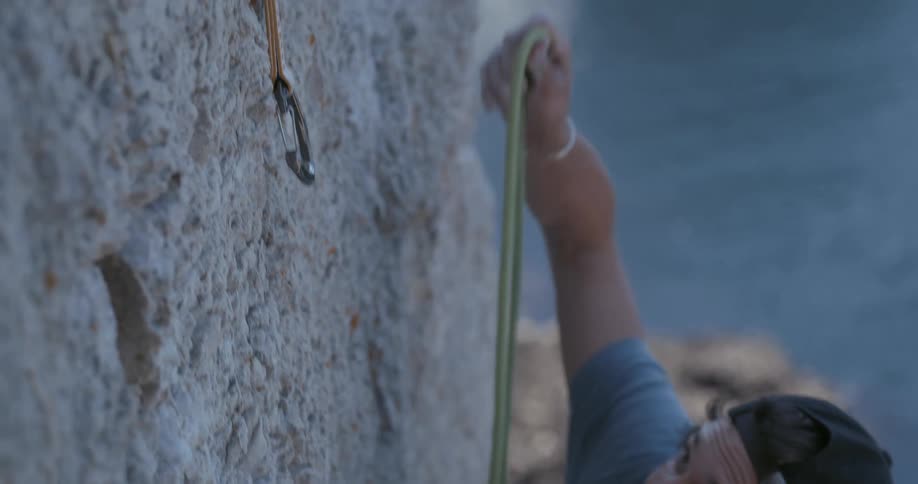 Man climbing the wall of a seaside mountain with seat belts
