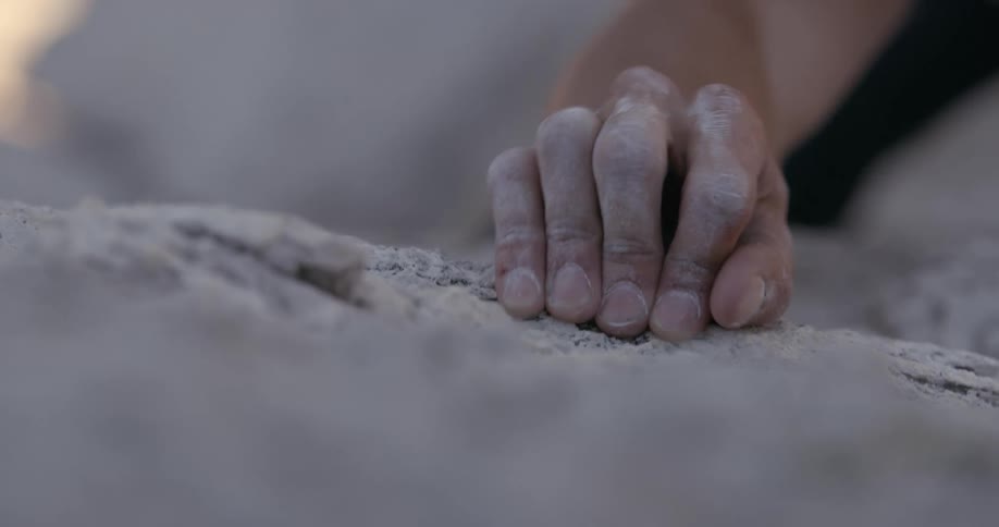 Hand of a man leaning on a rock while climbing a mountain