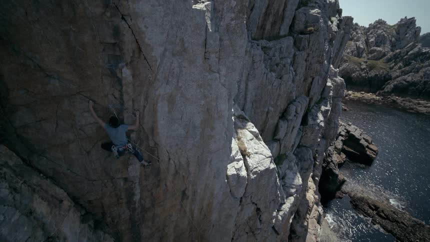 A man climbs a cliff near a coast