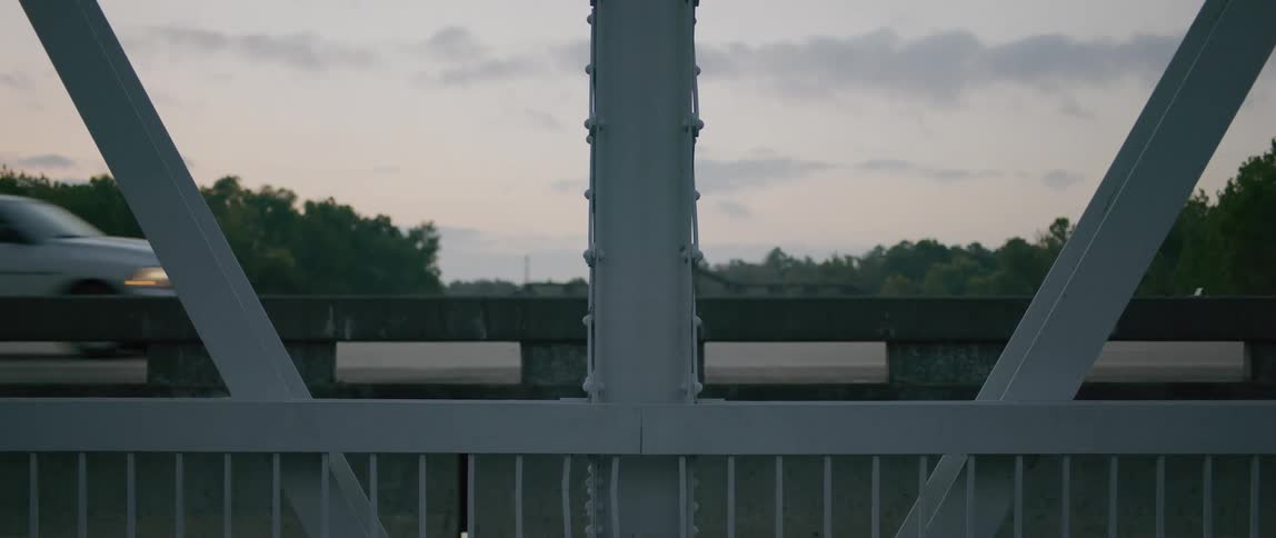 A steel bridge with passing cars in the evening