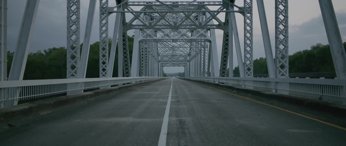 Cars drive on a road next to a bridge