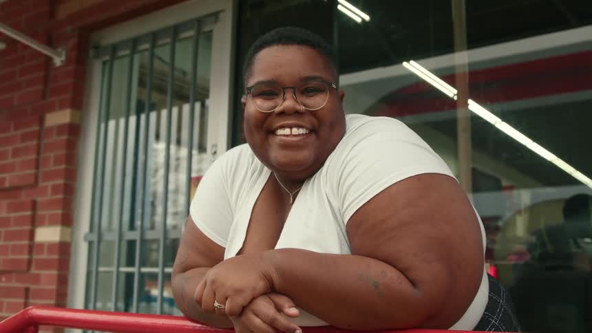 Woman resting her arms on a railing smiles and turns her head to face the camera