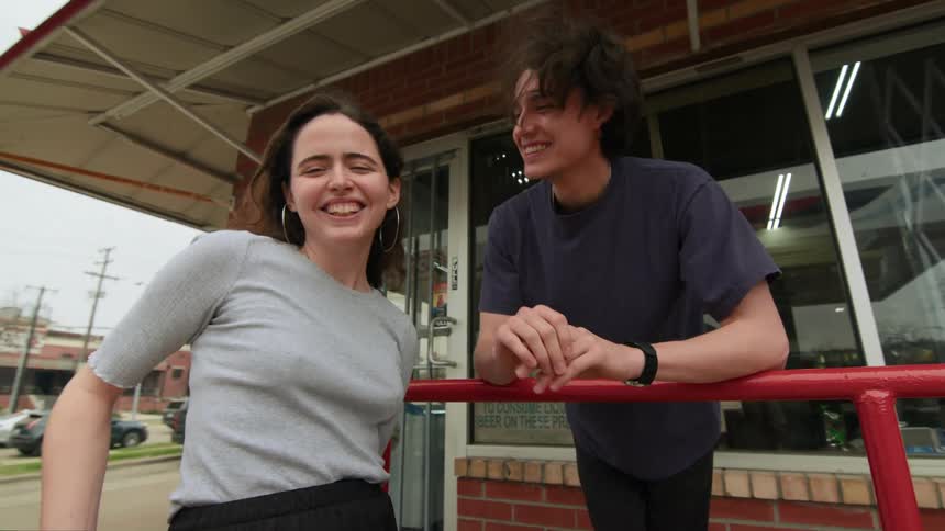 Man and woman friends outside an establishment smiling and talking