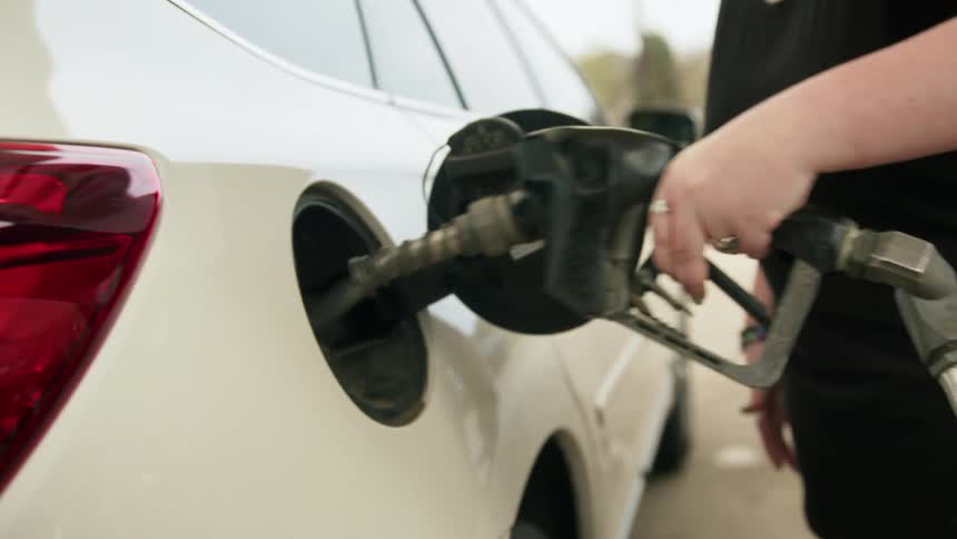 A woman pumps gas into her car