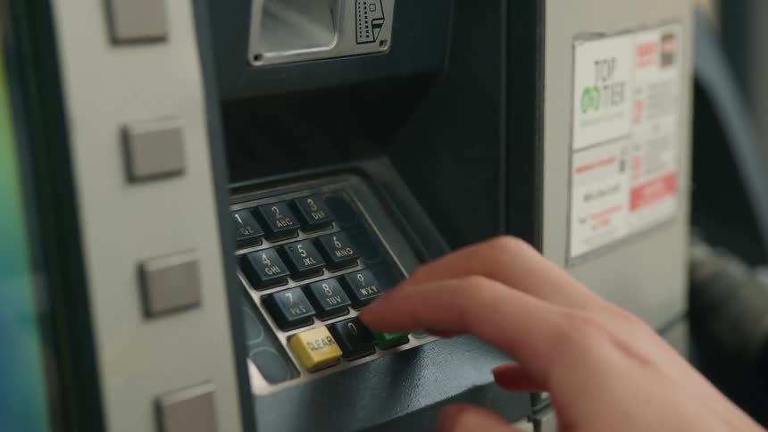 Closeup of a persons hands typing on a machine with gas station numbers