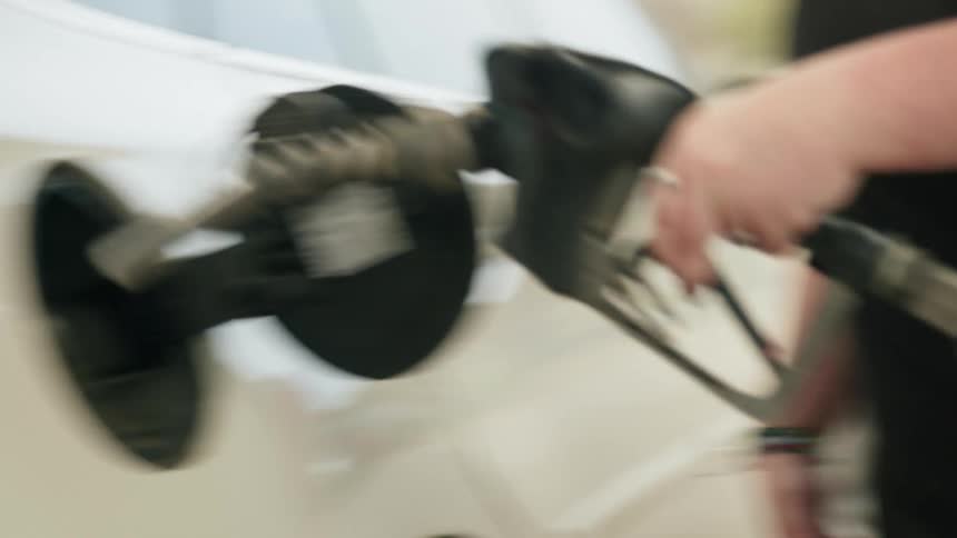 Closeup of a persons hands removing the gas pump valve and placing it in his car