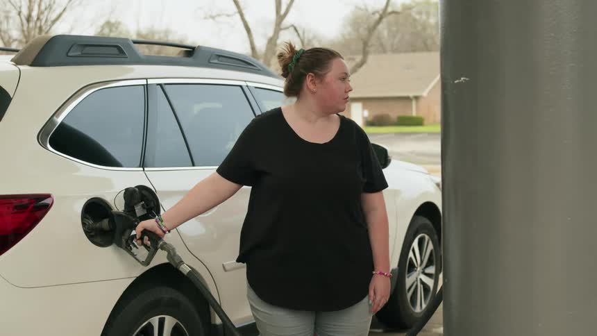 A woman is filling her gas tank