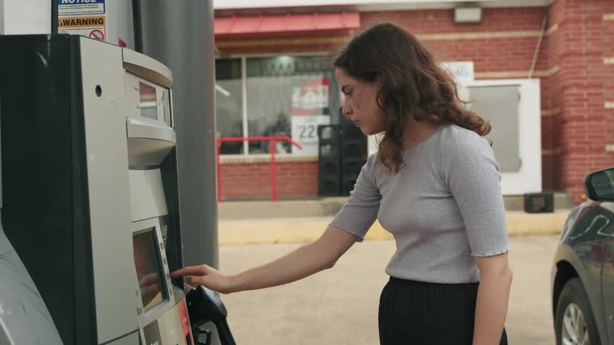 A woman inserts her card at a gas pump using the pin pad