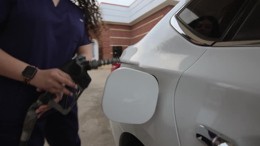 A woman pumps gasoline into a car