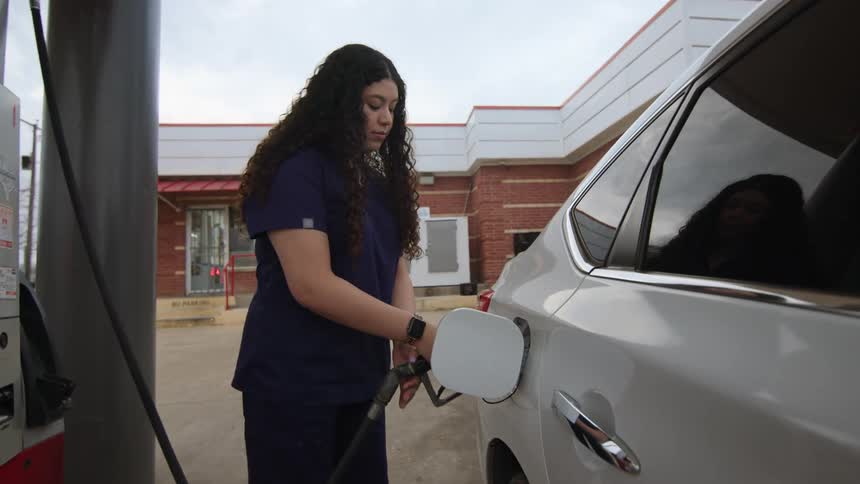 Woman taking the valve from a fuel pump and filling up her car