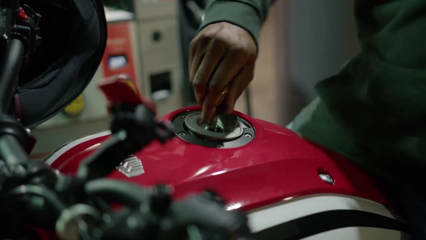 Mans hand putting the key in the fuel tank of his motorcycle and opening it