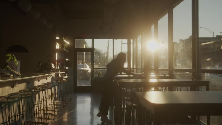 The employee is cleaning the tables with a rag