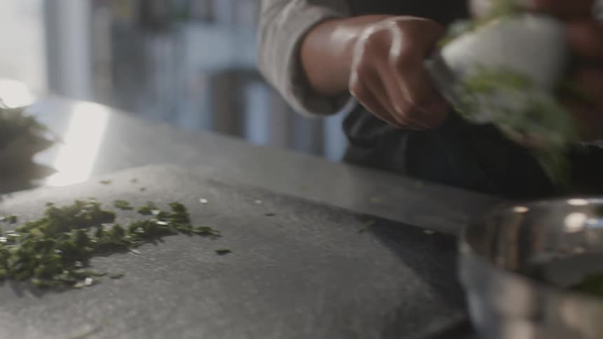 Cook adds chopped vegetables to bowl while cooking alone in the kitchen