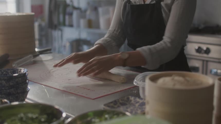 A womans hands on a counter preparing a dough