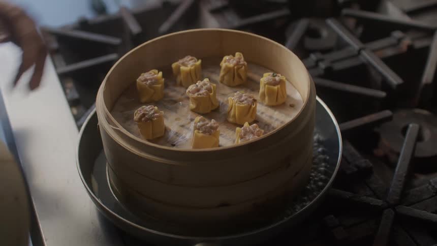A person cooks dumplings on a gas powered stove