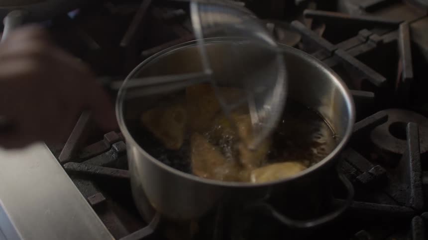 A person is mixing the food in the pot of hot oil