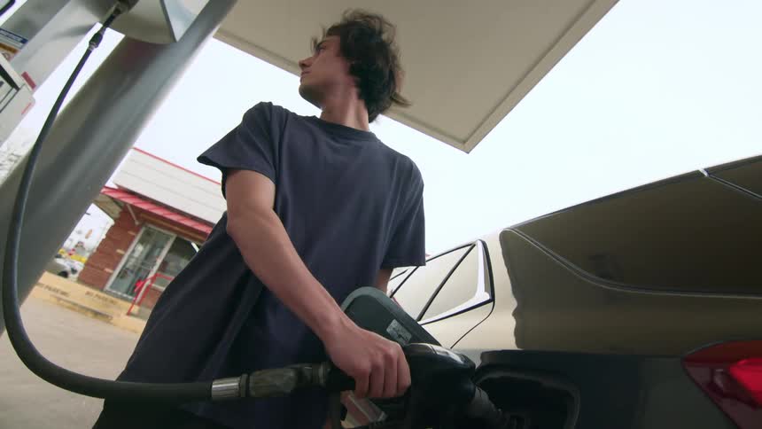 Young man with fueling his vehicle at gas station