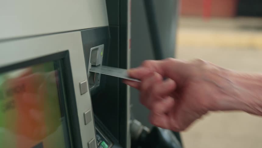 Closeup of an elderly womans hand removing her card from a fuel pump at a gas station