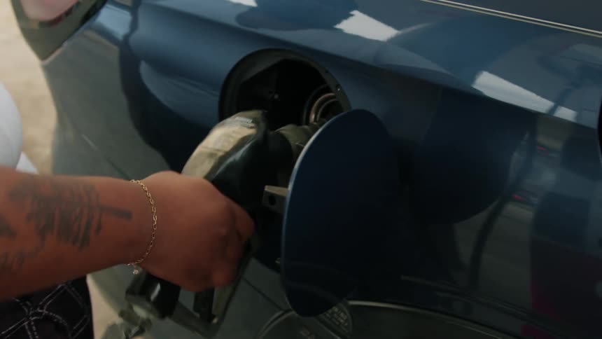 A black woman pumps gas