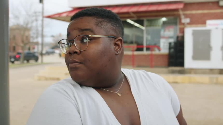 A black woman pumps gas into a car