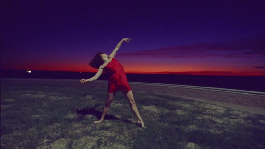 A woman is dancing by the shore