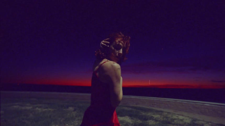 Woman dancing scenically outdoors at night with red sky