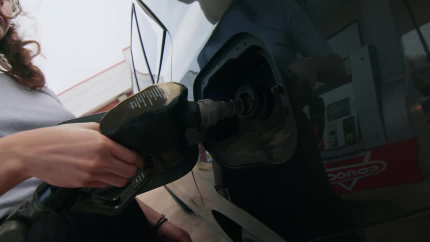 A woman pumps gas