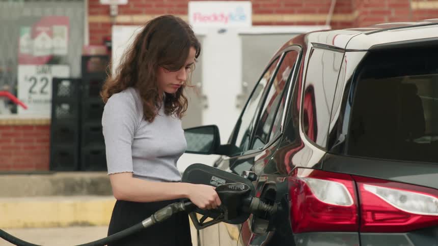 A woman fuels up at a gas station