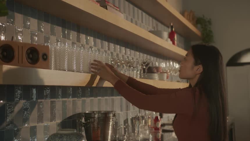 Woman pulls glassware to the edge of shelving for uniformity
