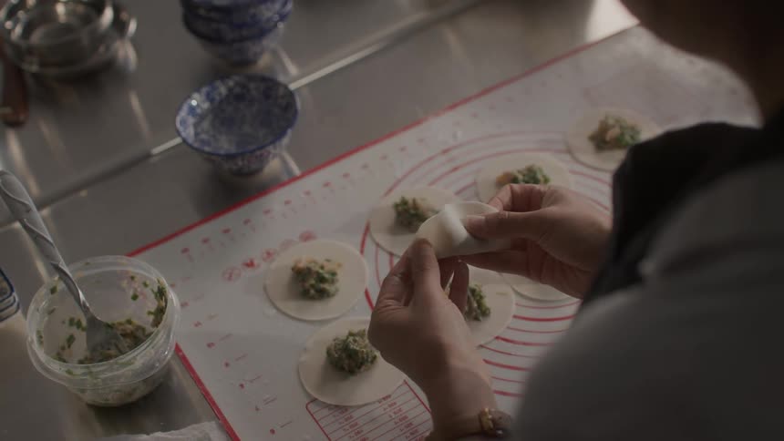 A womans hands preparing nikuman dumplings and on a counter