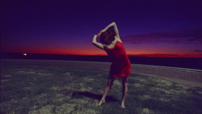 A woman in a red dress dances outside