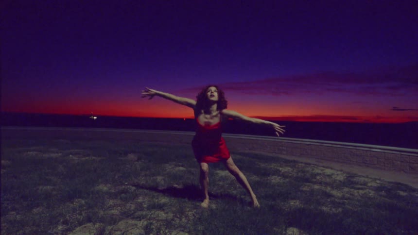 A woman in a red dress dances outdoors