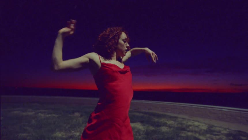 A woman in a red dress dances outside