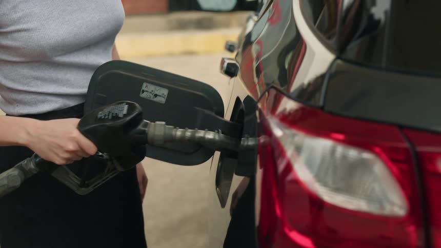 A woman pumps gas into a car