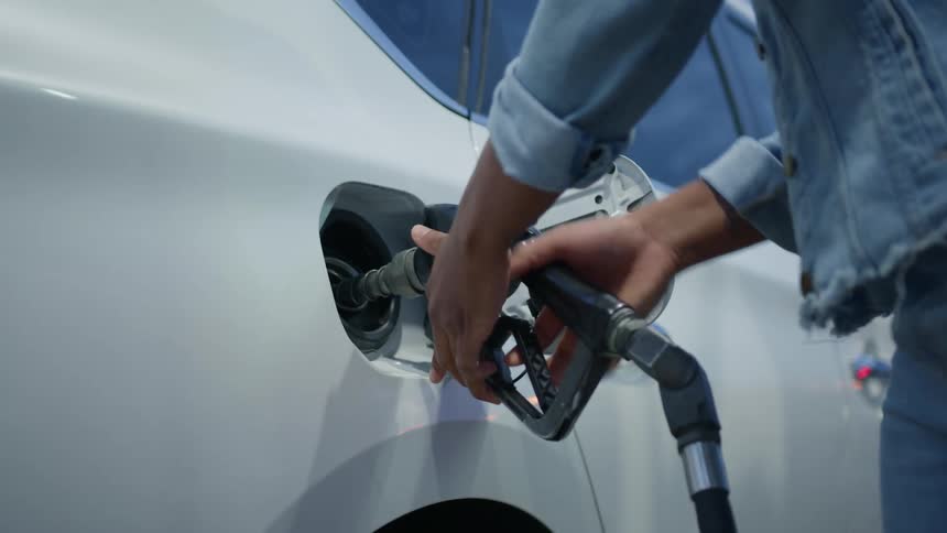 Hands of a woman taking a valve from a pump at the gas station and filling up her car