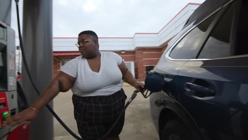 Woman picking up the fuel pump valve and filling up her vehicle