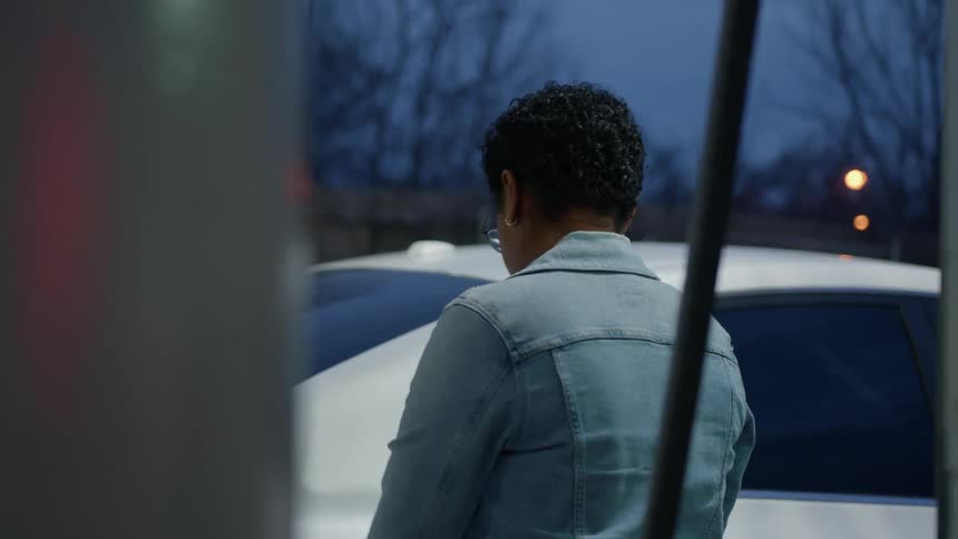 A woman is filling her gas tank at the pump