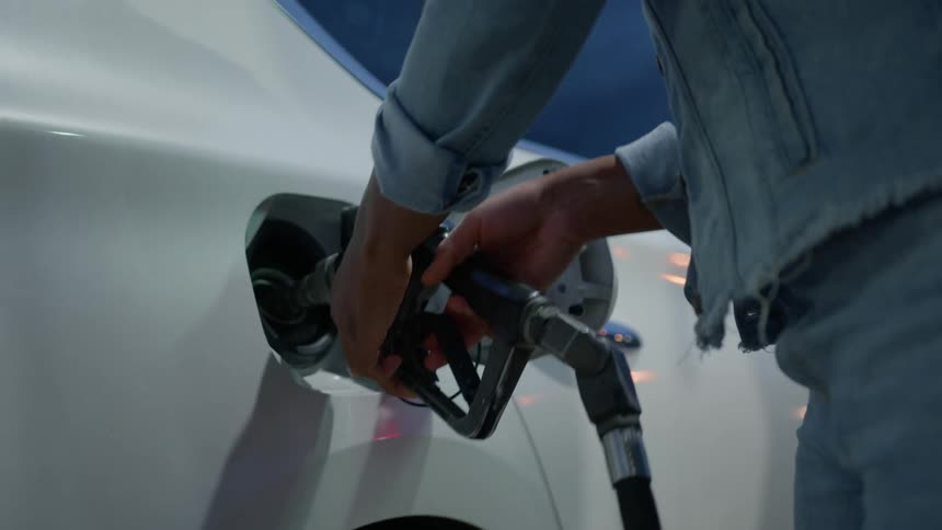 A woman inserts the nozzle of a gas pump into her fuel tank