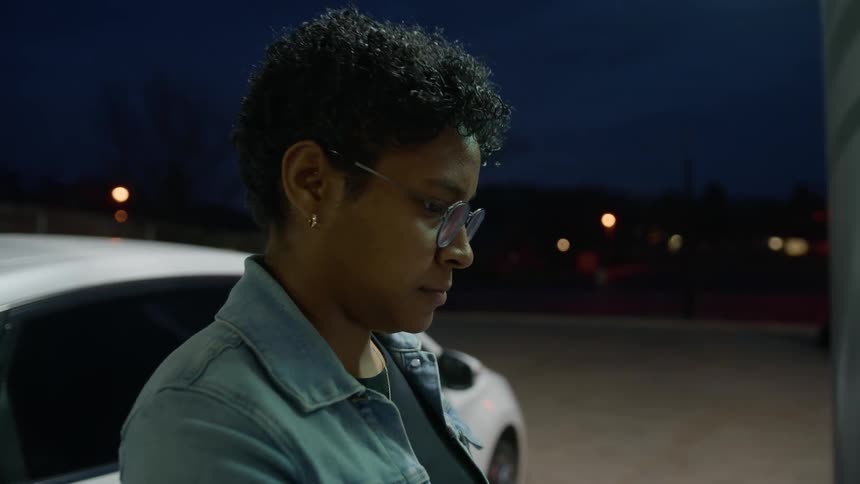 Portrait of a woman tinkering with a machine at a gas station at night