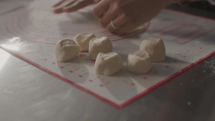 A woman carefully prepares dumplings