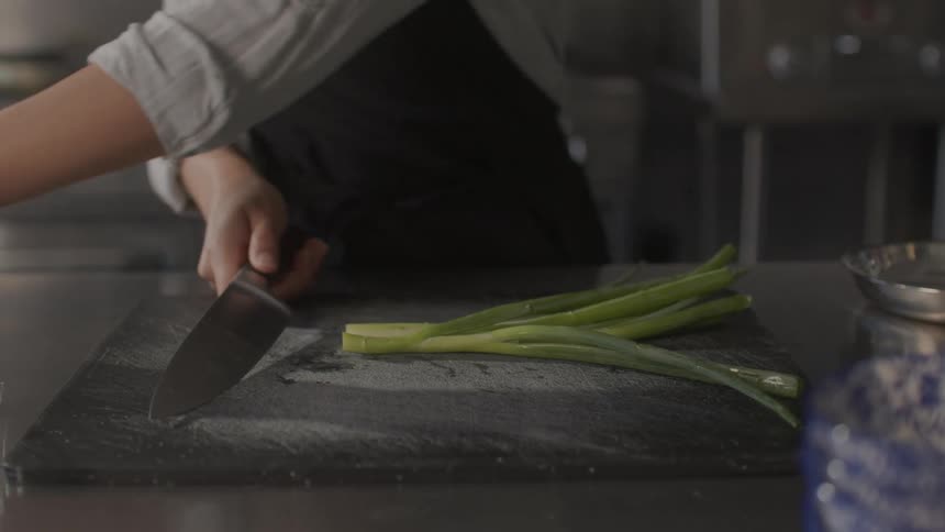 A cook is cutting vegetables in the kitchen