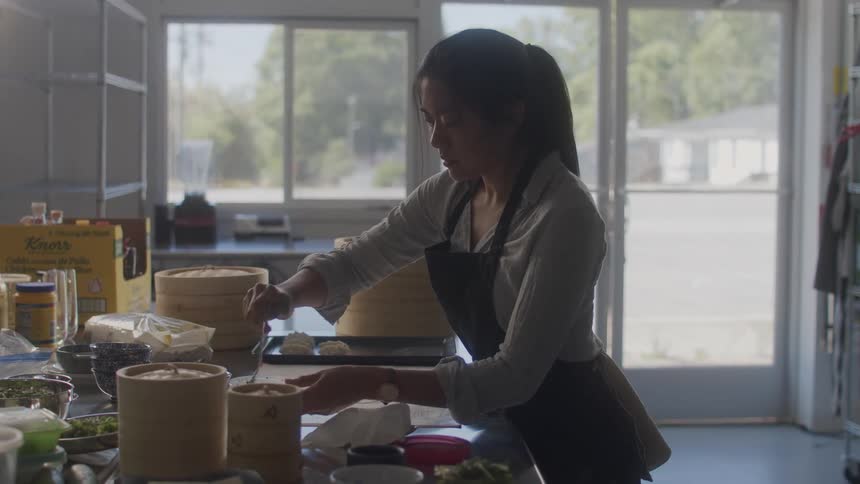A woman scoops ingredients out of a canister in a home kitchen