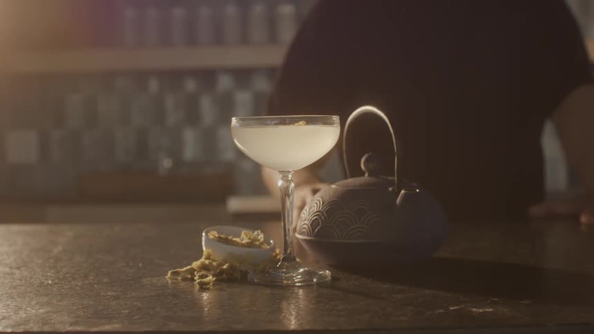 Cocktail with spices on a counter and a mans hands placing a kettle next to it