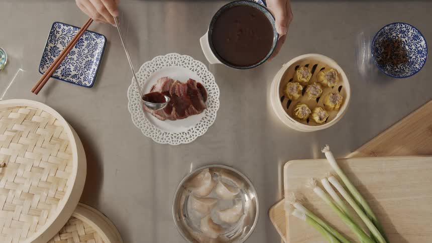 A person pours gravy over the sliced meat
