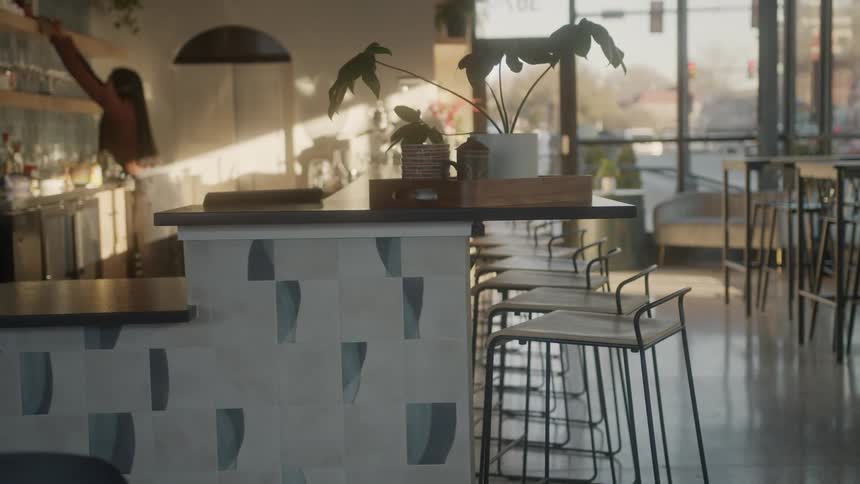 Woman at a restaurant counter placing objects on the shelf during the day
