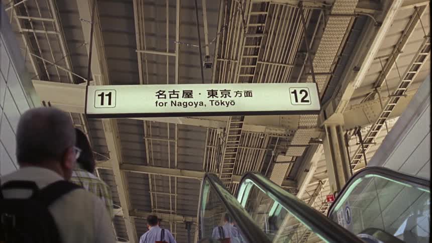 People use escalator near station sign that provides directions to routes