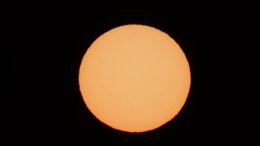 Bright yellow sun is seen zoomed in against a dark sky