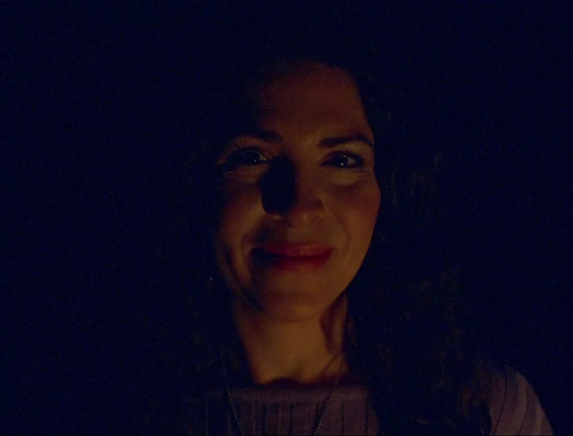 Portrait of a curlyhaired woman smiling with a loop of lights passing over her face