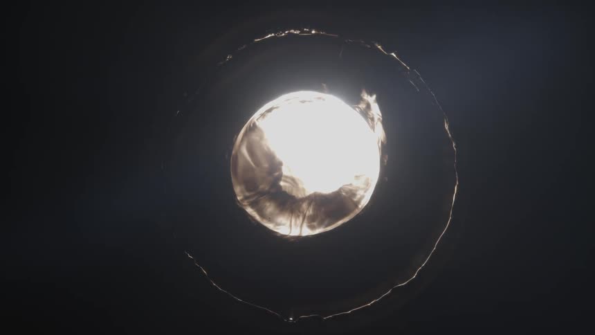 A round bright white object appears on a black background and then contracts and disappears