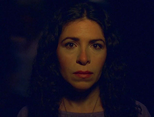 The face of a woman who is standing looking straight ahead while a light is rotating orbiting her and casting a shadow on her face
